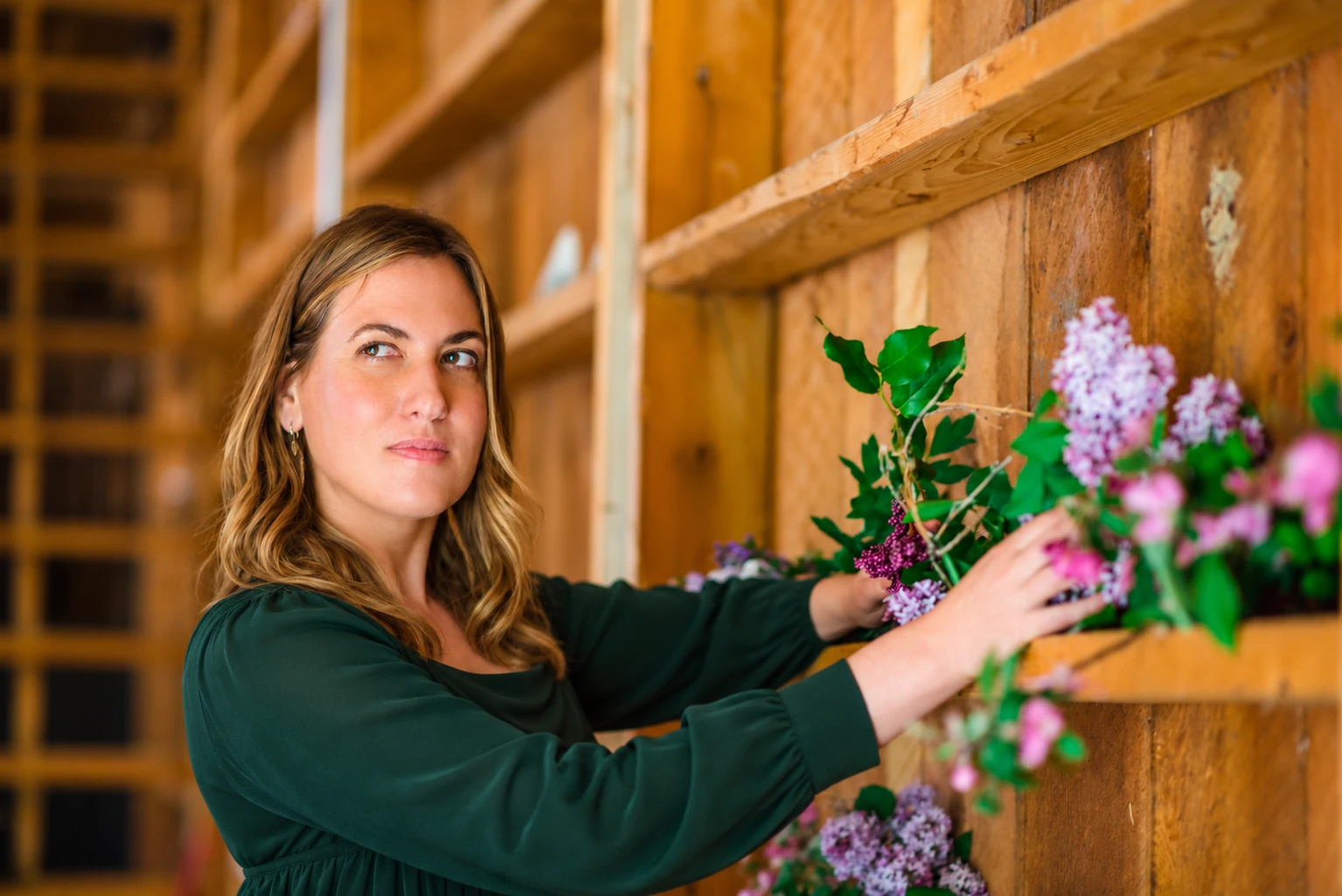 Dr. Michele Burklund in a forest-green dress arranging purple flowers