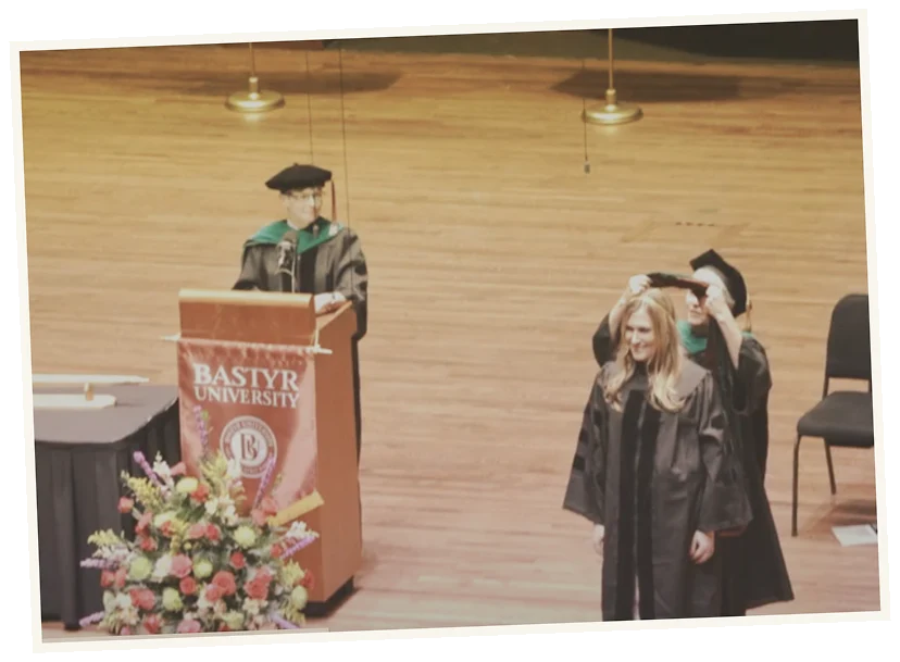 Graduation ceremony at Bostyr University with a student receiving her diploma and university officials present.